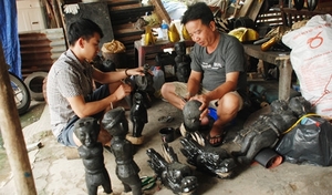 (C) An Huy, Thanh Nien, 人形に漆を塗るオアインさん(右)と息子(左)